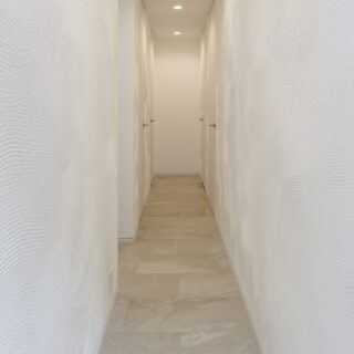 パブリックとプライベートを分けている漆喰壁の廊下。主寝室やウォークインクローゼットなどにつながる