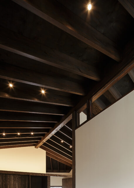 2階LDKの天井は屋根の形状を生かした。古色塗装された梁がリズミカルに並ぶ、ダイナミックな空間