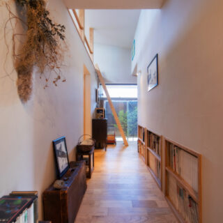 上田さんは古家具を置くため、あえて広い幅の廊下を提案。暗くなりがちな廊下も屋根からの光が降り注ぎ、古家具の質感をより美しくみせてくれる。反対側には、和室の押し入れの下のスペースを活用した本棚も設けた。