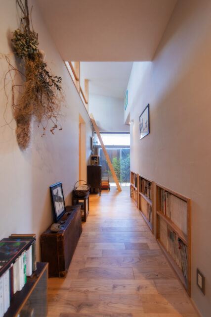 上田さんは古家具を置くため、あえて広い幅の廊下を提案。暗くなりがちな廊下も屋根からの光が降り注ぎ、古家具の質感をより美しくみせてくれる。反対側には、和室の押し入れの下のスペースを活用した本棚も設けた。