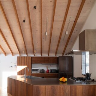 特注したキッチン。天板はマットなステンレス、側面や収納はクルミの無垢板で、空間の木の雰囲気に馴染む