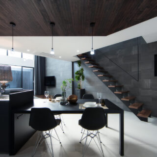 キッチンは、あえて天井を低くすることで、吹き抜け空間のリビングがより広さを感じさせる。階段の手すりも宙に浮くようなデザインでスッキリした空間に