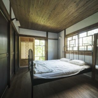 クライアントご夫妻の寝室は約6畳。写真左手は押入れで、建具は地域の方から譲ってもらった古い扉を使っている。フラットな天井の上は小屋裏収納となっている