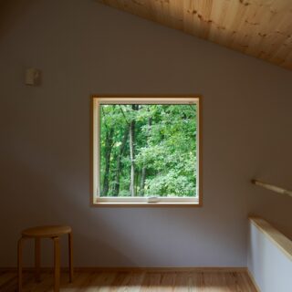 2階の寝室。椅子に座ったときの目線の高さにピクチャーウインドーを設置。森林の緑を眺めてくつろげる