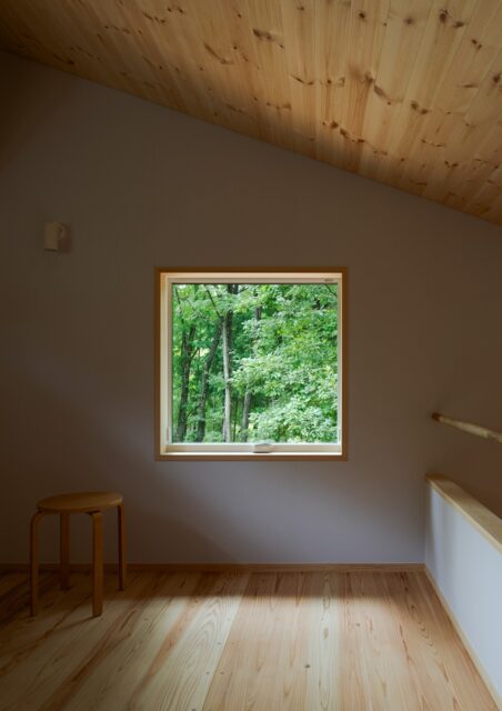2階の寝室。椅子に座ったときの目線の高さにピクチャーウインドーを設置。森林の緑を眺めてくつろげる