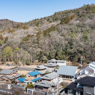 画像右側、大きな片流れ屋根の建物が「山裾の家」。家は、美しい山の景色や視界が開ける立地条件を生かせるように計画した