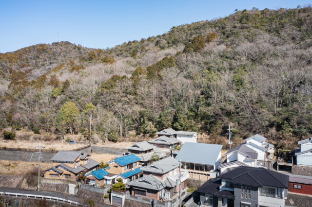 画像右側、大きな片流れ屋根の建物が「山裾の家」。家は、美しい山の景色や視界が開ける立地条件を生かせるように計画した