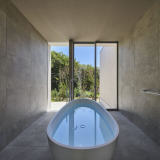 バスルームの中央には、卵型の浴槽が鎮座。窓の先には森の緑と青空が広がり、露天風呂気分が味わえる。