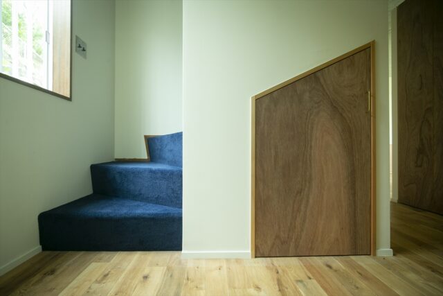 1階階段。画像右の扉は、リノベーションによって新しく計画された階段下収納。階段には、要望から絨毯を敷いた