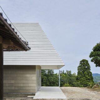 K邸へのアプローチは、母屋の前を通って。深い軒下は、雨に当たらない駐車スペースと作業スペースを生んだ。