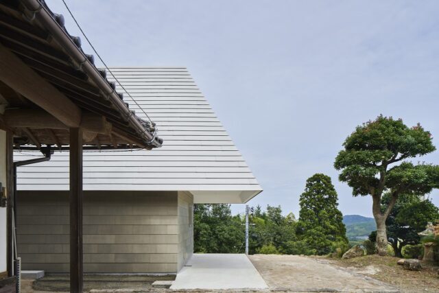 K邸へのアプローチは、母屋の前を通って。深い軒下は、雨に当たらない駐車スペースと作業スペースを生んだ。