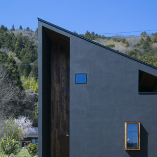 家は大胆な片流れ屋根のフォルムに、玄関部分の上まで貫かれた異なる素材の壁のラインと、目を引くデザイン