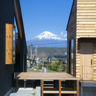 母屋（左）、小屋（右）ウッドデッキ（中）。母屋の玄関に入るときに見える大迫力の富士山。建物を２つに分けなければ見られなかった景色だ。立地条件から近隣の家は富士山と反対の南側に窓を設けることが多く、この眺めはこのエリアでも貴重だという
