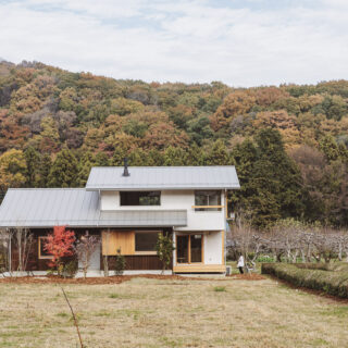 外観。画像左側にあたる西以外は、山（北）、原っぱ（南）、伸びやかに広がる眺望（東）とすこぶるいい環境の中にある「にちにちの家」。この環境に似合う木の家として、モダンすぎず、野暮ったくもないデザインを目指した。白、シルバーに木の風合いの茶をプラスした、軽やかな家