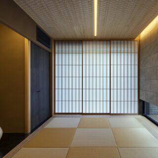 和室。畳を囲う板張りの部分や天井はナグリ仕上げとしたほか、右壁面にはタイルを採用するなど上質な素材をふんだんに使用。スリットライトが空間を引き締めている