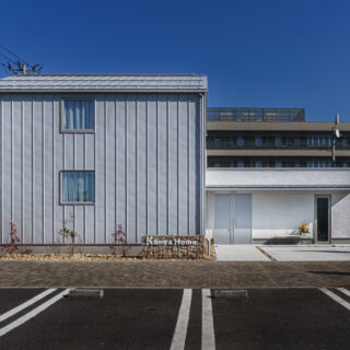 外観正面。駐車場は共用のもの（手前）があるため本来は必要ないが、実際は必要となるためあえて設置した。右側のドアは除雪道具を格納することもできる多目的ルーム入口。手前が西側となり、西日を避けるために開口部は最小限にした