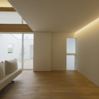 １階フリールーム。画面左側にあるリビングとの仕切りには天井から吊るパーテーションを採用。床面のレール不要で、開放時の一体感を高めた。間接照明をラインのように入れ、明るさを確保しながら天井や壁をすっきりと見せた
