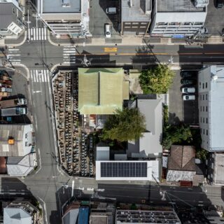 大阪市内にある浄土真宗大谷派 長源寺を空から撮影。太陽光のパネルを載せているのが庫裏の子世帯、グレーの屋根がかかっているのが親世帯。2つの世帯はL字のプランで分かれているが、どちらも中庭の大きな桜を眺められる配置となっている