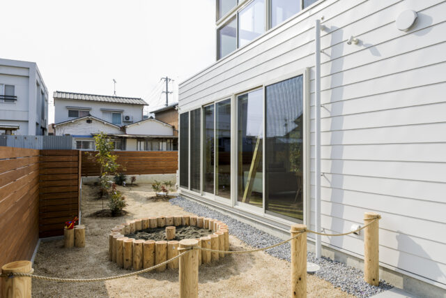 東側外部。道路から見える風景は公園をイメージ。ポールとロープを使い、「強すぎない、シグナルサインのような感じ」で外部と仕切った。砂場があったり、庭に高低差があったりと遊び場としてもこの上ない環境が整っている。高低差によって、植栽の高さにも変化が生まれる