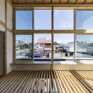 2階書斎。左は子ども部屋(子ども室)。大開口に沿ってカウンターを計画し、格子床を居場所として整えた。ラグを敷いて子ども室の床を拡張させればよい遊び場に。使用する目的に合わせてその都度床面を拡張するイメージだ。住宅街にあるとは思えないほどの視界の広がりが魅力的