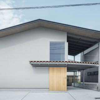 外観（正面）。周囲は住宅街で一般的な家であるため、奇抜な外観ではなく周囲に溶け込むシンプルなものとした。視線カットと断熱効果を高めるため、前面道路側の窓は最小限に。玄関ドアはバイクを土間に入れるため大きなものを造作した