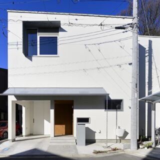 キューブ状で統一された外観。白い外壁は汚れにくい光触媒の左官材を用いた。リビングに光を採り込むための窓には、夏の日差しを防ぐために、L字型の庇を設けた