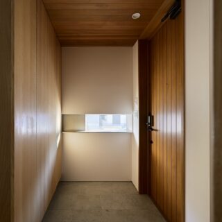 玄関はレッドシダーの軒天と石調の土間、ナラ材の収納など、自然な温かさを感じさせる空間。窓からの光が生み出す陰影が美しい。玄関扉も断熱性の高い木製のものを採用