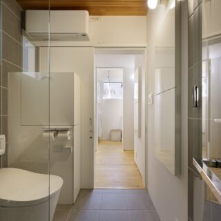 バスルームはホテルライクに。トイレ横の収納できるボックスは、扉を倒すことで脱衣カウンターとして利用できる。写真右側の壁埋め込みの収納も便利