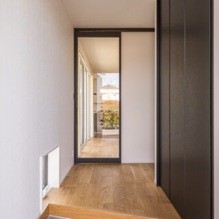 玄関ホール。ドアを全面ガラスにすることで、開放感と光を取り込む。框を長くするため、床は斜めに