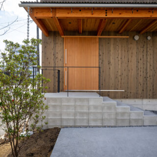 玄関は、コンクリート階段を上った先に。階段部分は建物本体と切り離すことで熱効率やシロアリ対策となるほか、異空間へ飛び込むイメージも。軒を深くとることで建物の構造面の補強にも。
photo：YASUO HAGIWARA