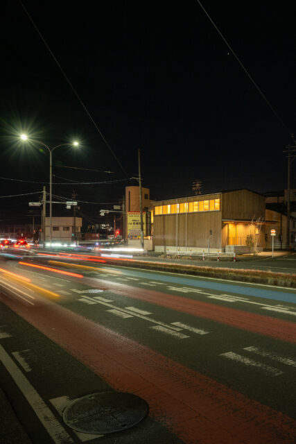 夜でもそれなりの交通量のある国道。室内の明かりが漏れるとともに、２階天井の現しの木組みの美しさがくっきりと見える。
photo：YASUO HAGIWARA