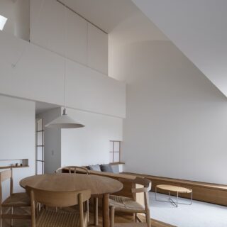 間接照明が各所に配され、シンプルな室内。吹き抜けでつながる2階の部屋は、造作家具（写真上部中央）で空間を閉じることもできる