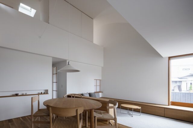 間接照明が各所に配され、シンプルな室内。吹き抜けでつながる2階の部屋は、造作家具（写真上部中央）で空間を閉じることもできる