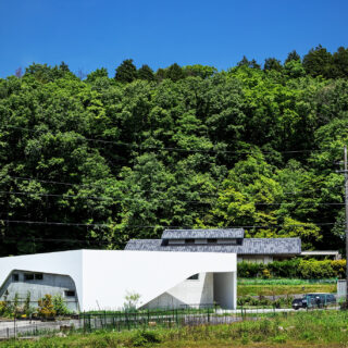 外観。利便性がよく、風光明媚な場所に建つ「西宮・里山の白い平家」。空の青や里山の緑に白い壁面が映える