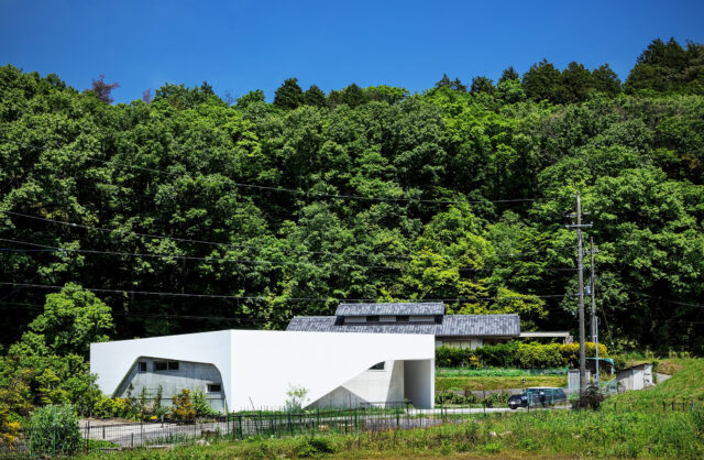 外観。利便性がよく、風光明媚な場所に建つ「西宮・里山の白い平家」。空の青や里山の緑に白い壁面が映える