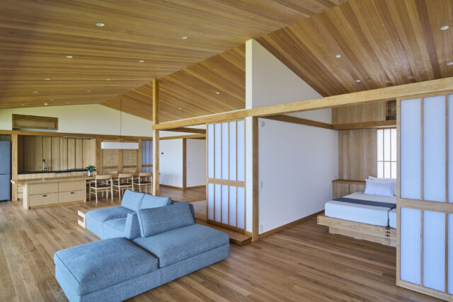 2階、リビングからキッチン方向を見通す。寝室に設けたエアコンの空気を部屋中に循環させられるよう、仕切り戸と天井までの間を空けた。また風の流れを計算し、高い断熱性も確保している。キッチンの壁面にもエアコンがあるが、寝室のものだけで十分涼しいという
