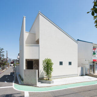 外観。お父様の要望により、塀を設けずオープンな外構に。郵便局利用者が塀の前に車を停めてしまうことを避けるための配慮である。2階左側はバルコニーで、直射を避けながらキッチンにやわらかな光を届ける設計