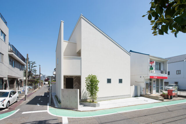 外観。お父様の要望により、塀を設けずオープンな外構に。郵便局利用者が塀の前に車を停めてしまうことを避けるための配慮である。2階左側はバルコニーで、直射を避けながらキッチンにやわらかな光を届ける設計