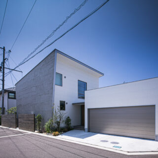 北東から見た外観。住居部分は、道路からの視線が届きにくい北面の高い位置に窓を開口。東の壁面と屋根が大きく張り出しているおかげで、正面からは気配すら感じられない。右の大きな窓は階段のもの。豊かに光を取り込み、家中に届ける