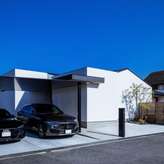 外観。画像左に走るのが幹線道路。手前の道路は交通量が少なく南にあたるため、庭は高さ2ｍのウッドフェンスで囲った南東（画像右）に配置した。豊かに光を取り入れながら視線や騒音を遮っている。さらに、庭の西側に建物を置いたことで、西日もコントロールできるようになった