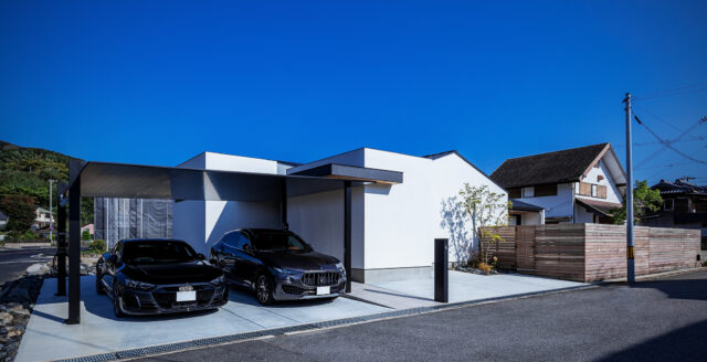 外観。画像左に走るのが幹線道路。手前の道路は交通量が少なく南にあたるため、庭は高さ2mのウッドフェンスで囲った南東(画像右)に配置した。豊かに光を取り入れながら視線や騒音を遮っている。さらに、庭の西側に建物を置いたことで、西日もコントロールできるようになった