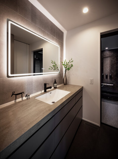 洗面脱衣室、浴室（右奥）。洗濯機を隣接するパントリーに置き、家事動線を短縮しつつ生活感を排除した