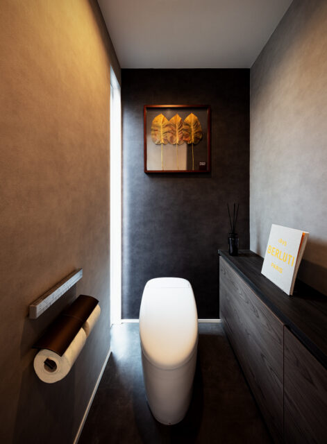 トイレ。左奥のスリットから中庭の光が漏れ入る。日射の変化により壁面の表情も変わる、高級感ある仕上がり