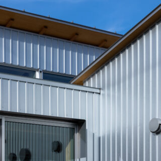 外壁はメッキ素地のガルバリウム鋼板を採用。反射を繰り返し輻輳する光が、外部空間の印象を豊かにする