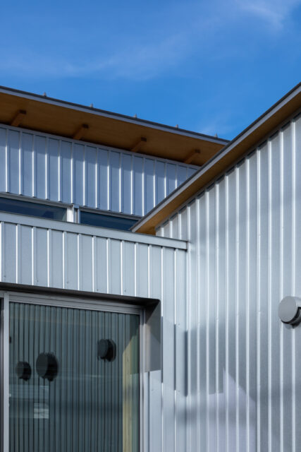 外壁はメッキ素地のガルバリウム鋼板を採用。反射を繰り返し輻輳する光が、外部空間の印象を豊かにする