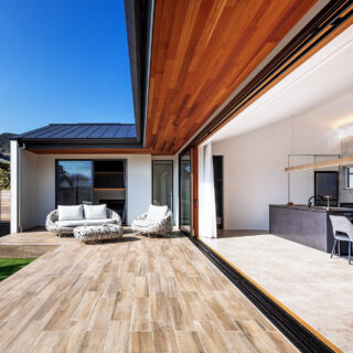 L字のテラスからLDKや庭を見渡す。正面は主寝室。テラスに張り出した庇は季節ごとの太陽高度を計算したうえで深さを計画。LDKも主寝室も一年を通して過ごしやすい。テラスは木目調パネル、LDKの床はタイルを取り入れたおかげで掃除しやすく、庭との行き来が気軽になった