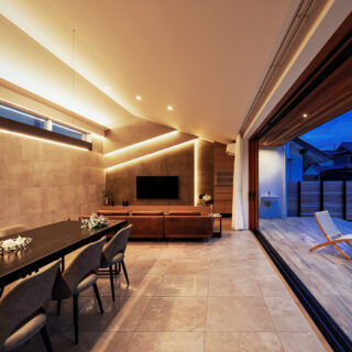 LDK（左）、テラス（右）。勾配天井は最高3.7mの天井高があり、開放感抜群。天井に極力照明を設けず、ライン状に配置した間接照明によって明るさの確保とデザイン性を両立させた