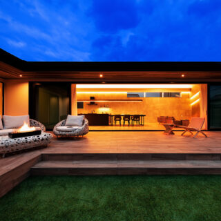 庭から家を見る。庭からテラス、室内までがひとつに繋がる大らかな家だ。大人数の来客時でも、皆がそれぞれ居場所を見つけやすいのも魅力。夜間はシンプルなライン状の照明によって、昼間とはまた違った洗練さを醸し出す