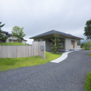 道路側から見た外観。建物の一角を屋根付きのテラスのような、用途を決めない空間として計画した。大きな洗濯物干しなど、便利使用されている。小高い丘の途中に外構が埋まっているよう。見た目も楽しい丘は高さ1.5ｍ程度あり、目隠しとしての役目を果たしている