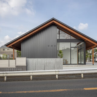 敷地の東を走る街道から見た「大屋根の家」。邸内には2階もあるが、切妻屋根をゆったりかけたシンプルなデザインで「平屋風の日本的な家」という要望に応えた。東面の約半分がガラス張りになった斬新さも魅力